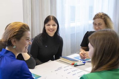 Darbsemināra dalībnieki pie galda strādā grupā