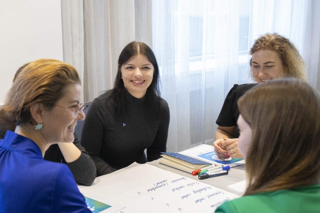 Darbsemināra dalībnieki pie galda strādā grupā